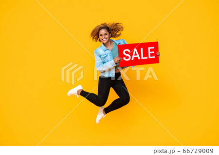 Surprised smiling woman jumping with red sale sign 66729009