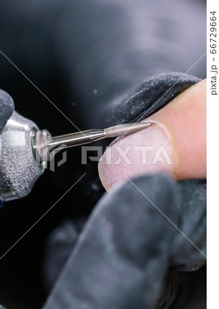 Process manicure close-up. Preparation for hardware manicure. Beautician in rubber gloves cuts the cuticle and processes nails. 66729664