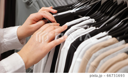 Female hands sorting cotton pullovers on a hanger in a clothing store 66731693