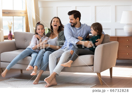 Excited mother and father having fun with children on couch Excited mother and father having fun with children on couch 66732828