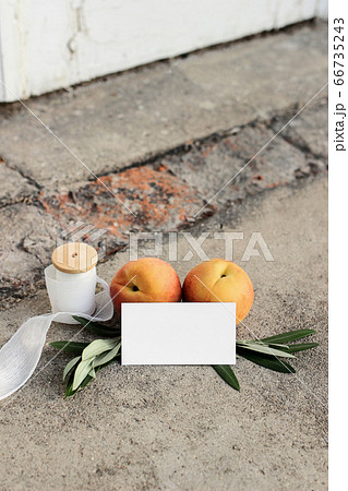 Summer wedding still life scene. Blank business card, invitation mock-up. Olive branches, silk ribbon and peaches fruit on grunge concrete background. Blurred old white door. No people, vertical Summer wedding still life scene. Blank business card, invitation mock-up. Olive branches, silk ribbon and peaches fruit on grunge concrete background. Blurred old white door. No people, vertical 66735243