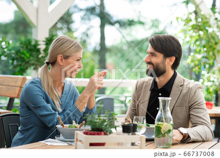 Happy couple sitting outdoors on terrace restaurant, talking. Happy couple sitting outdoors on terrace restaurant, talking. 66737008