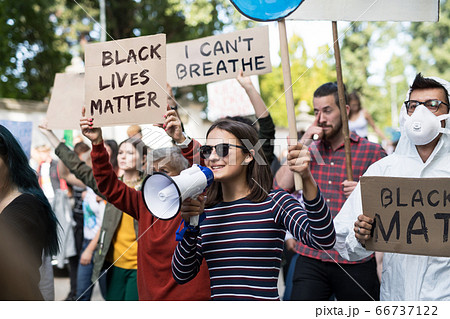 Black lives matters protesters with megaphone holding signs and marching outdoors in streets. 66737122