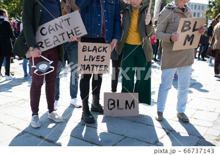 Unrecognizable black lives matters protesters holding signs and marching outdoors in streets. 66737143
