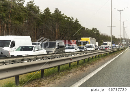 Highway interstate road with car traffic jam and tree forest on background. Motorway bumber barrier gridlock due country border control point. Vehicle crash accident and queue bottleneck on freeway Highway interstate road with car traffic jam and tree forest on background. Motorway bumber barrier gridlock due country border control point. Vehicle crash accident and queue bottleneck on freeway 66737729