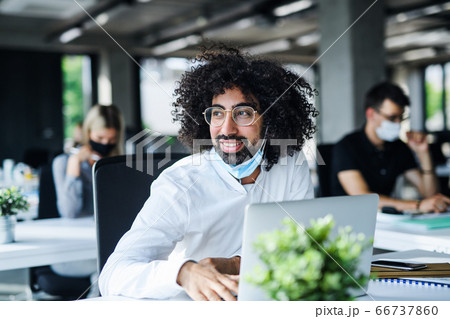 Portrait of young man with face mask back at work in office after lockdown. 66737860