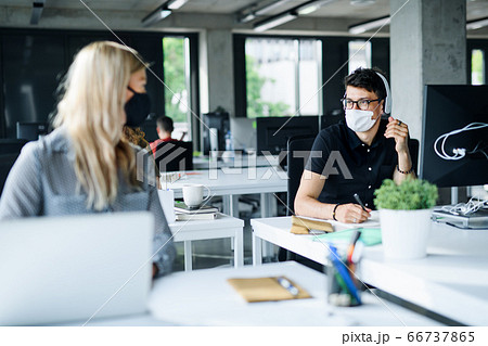 Young people with face masks back at work or school in office after lockdown. 66737865