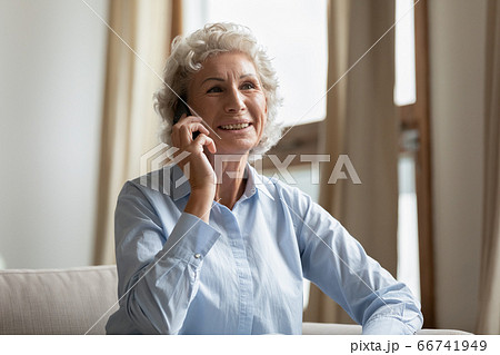 Middle-aged woman enjoy pleasant conversation with relatives using smartphone Middle-aged woman enjoy pleasant conversation with relatives using smartphone 66741949