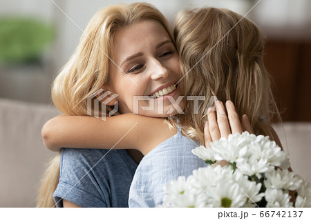 Candid mother hugs little daughter express gratitude for white flowers 66742137