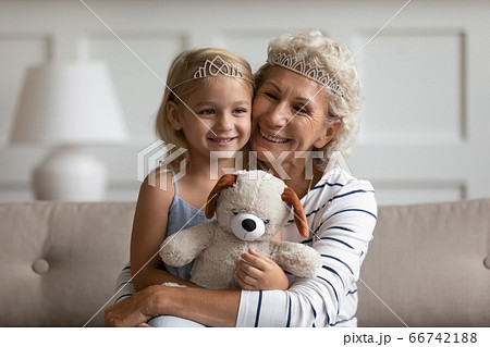 Grandmother hugging granddaughter sitting on couch play games at home 66742188