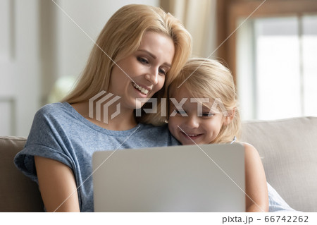 Mother sitting on couch with daughter having fun using laptop Mother sitting on couch with daughter having fun using laptop 66742262
