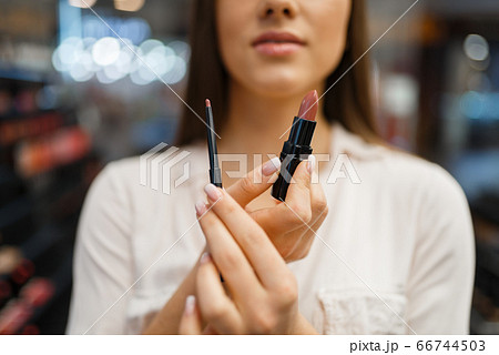 Woman shows lipstick and liner in cosmetics store 66744503