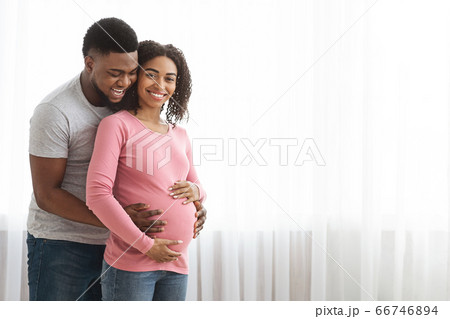 Cheerful black man touching his pregnant wife belly 66746894