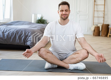 Man Meditating Sitting In Lotus Position Relaxing At Home 66746895