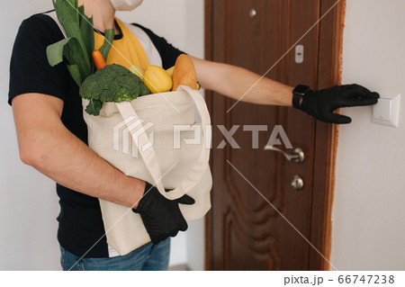 Delivery man in mask and gloves bring fresh food to customer's home. Stay home. Online shopping concept. Middle selection Delivery man in mask and gloves bring fresh food to customer's home. Stay home. Online shopping concept. Middle selection 66747238