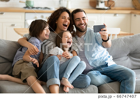Close up happy parents with little children using smartphone together. Close up happy parents with little children using smartphone together. 66747407
