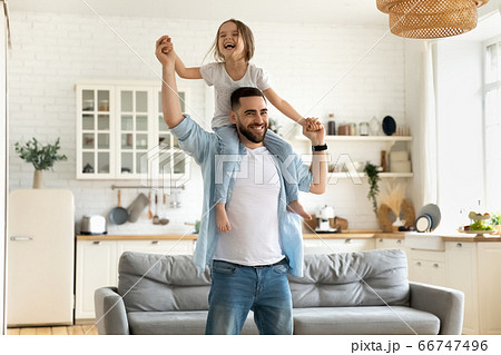 Happy little daughter sitting on father neck piggybacking playing game. 66747496