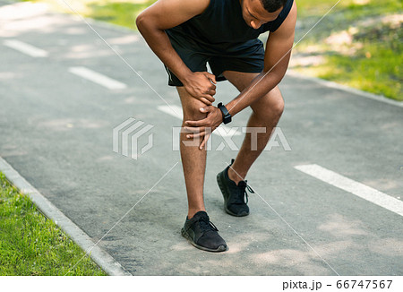 African American jogger suffering from pain in knee during his morning run at park African American jogger suffering from pain in knee during his morning run at park 66747567