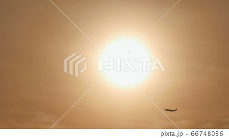Take off the plane in the distance against the background of sunrise or sunset. Silhouette of an airplane. Airplane in the sky at sunset. 66748036