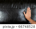 The woman's hand touching the surface of the sofa. 66748528