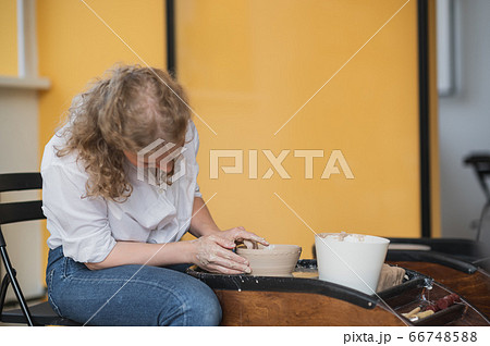 Potter makes the clay product with pottery modeling tools on the potter's wheel. 66748588