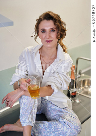 Portrait of a girl sitting in the kitchen with a cup of tea 66749707