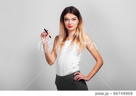 Business Woman drawing with pen on virtual screen with copy space for text on gray background 66749909