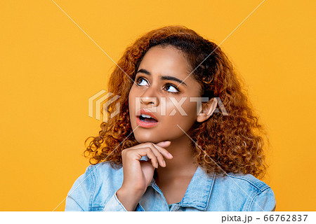 Mixed African woman thinking with hand on chin and looking up to space Mixed African woman thinking with hand on chin and looking up to space 66762837