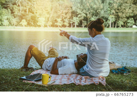 Asian couple lover sitting a relax River side in the public park. working with a notebook 66765273