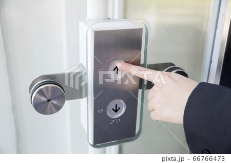エレベーターのボタンを押す若い女性手元 66766473