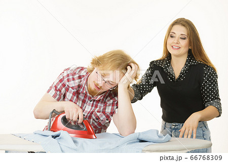 Happy woman and bored man ironing clothes 66768309