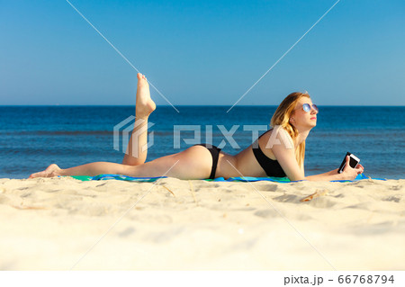 Summer vacation Girl with phone tanning on beach 66768794
