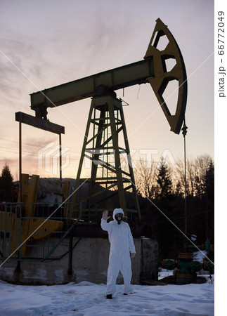 Ecologist standing near oil well pump jack. Ecologist standing near oil well pump jack. 66772049
