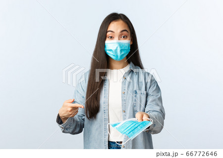Social distancing lifestyle, covid-19 pandemic everyday life and leisure concept. Cheerful cute asian girl explain importance of medical mask during coronavirus disease outbreak 66772646