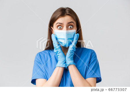 Covid-19, preventing virus, health, healthcare workers and quarantine concept. Close-up of shocked and surprised female nurse or doctor in blue scrubs, medical mask, gasping astonished big news 66773307