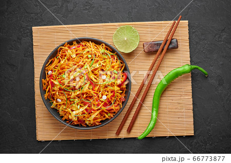 Chinese Bhel in bowl on black table top. Indo-Chinese cuisine street food dish with schezwan sauce Chinese Bhel in bowl on black table top. Indo-Chinese cuisine street food dish with schezwan sauce 66773877