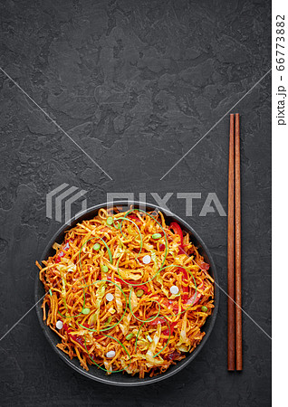 Chinese Bhel in bowl on black table top. Indo-Chinese cuisine street food dish with schezwan sauce Chinese Bhel in bowl on black table top. Indo-Chinese cuisine street food dish with schezwan sauce 66773882
