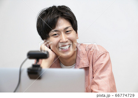 オンラインミーティング　イメージ　ウェブカメラに向かって話す若い男性 66774729