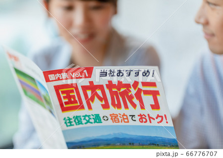 旅行のパンフレットを見ながら計画を立てる男女 66776707