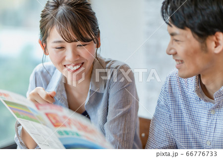 旅行のパンフレットを見ながら計画を立てる男女 66776733