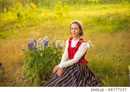 Latvian woman in traditional clothing in field. Latvian woman in traditional clothing in field. 66777237