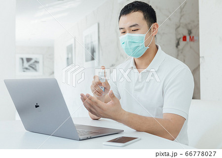 A man using the spray while working at home with his mask on 66778027