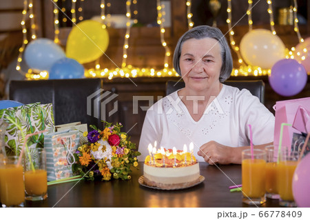 Senior woman with birthday cake at anniversary Senior woman with birthday cake at anniversary 66778409