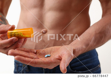 Athletic young man with perfect abs holding pills 66778447