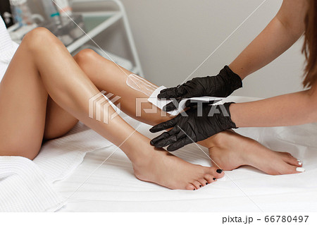 Beautician makes depilation young woman on her feet with wax, liquid sugar 66780497