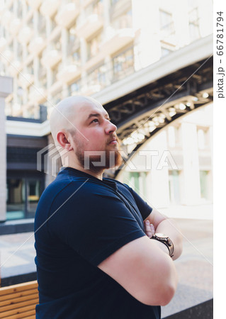 portrait of a bald handsome bearded man in a black t-shirt on the street, who looks away. portrait of a bald handsome bearded man in a black t-shirt on the street, who looks away. 66781794