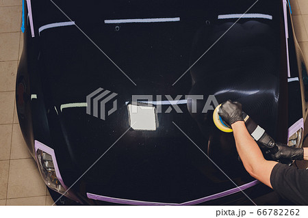 Car detailing - Hands with orbital polisher in auto repair shop. Selective focus. 66782262