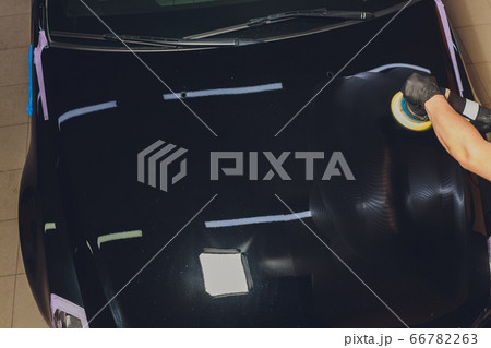 Car detailing - Hands with orbital polisher in auto repair shop. Selective focus. 66782263