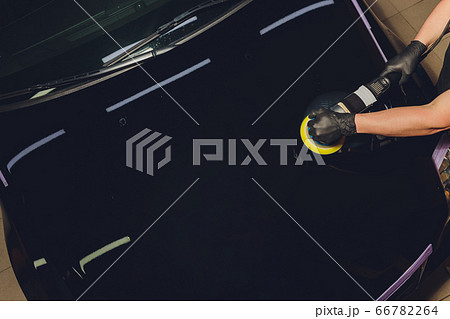 Car detailing - Hands with orbital polisher in auto repair shop. Selective focus. 66782264