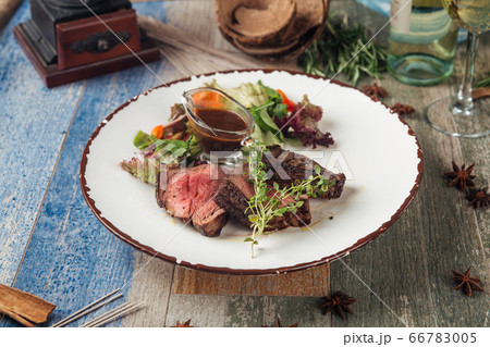 Tender steak mignon with greens and sauce 66783005